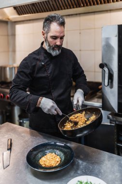 Yakışıklı sakallı profesyonel şef restoran mutfağında çalışıyor. O, balık ve deniz ürünleriyle sağlıklı lezzetli yemekler hazırlar..