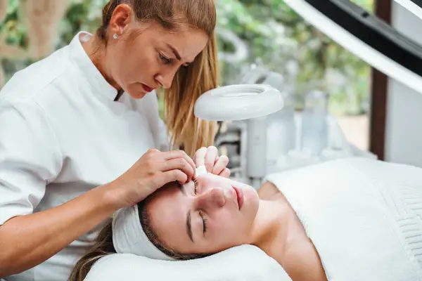 Stock image Professional beautician manually removing acne and pimples from young woman's face in a modern equipped beauty spa studio. Beautification and skin health concept.