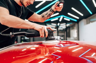 Modern bir araba atölyesinde profesyonel araç cilalama ve detay verme servisi. Parlak ışıklandırılmış çalışma alanı, büyük ışıklı. Yüksek kaliteli araba valelik kavramı.