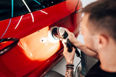 Modern bir araba atölyesinde profesyonel araç cilalama ve detay verme servisi. Parlak ışıklandırılmış çalışma alanı, büyük ışıklı. Yüksek kaliteli araba valelik kavramı.