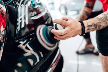 Modern bir araba atölyesinde profesyonel araç cilalama ve detay verme servisi. Parlak ışıklandırılmış çalışma alanı, büyük ışıklı. Yüksek kaliteli araba valelik kavramı.