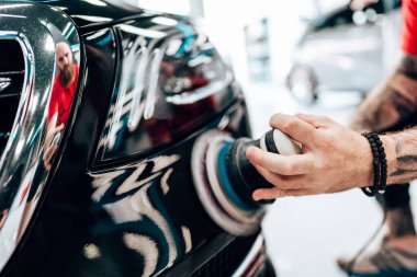 Modern bir araba atölyesinde profesyonel araç cilalama ve detay verme servisi. Parlak ışıklandırılmış çalışma alanı, büyük ışıklı. Yüksek kaliteli araba valelik kavramı.