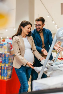 Çekici orta yaşlı çift yeni bebekleri için kıyafet ve alet almaktan zevk alıyor. Bebek dükkanında ya da mağazada güzel bir çift. Bebek konsepti bekleniyor..
