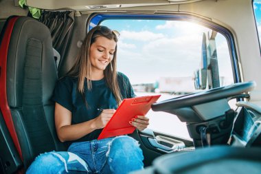 Profesyonel kamyon şoförünün uzun bir yolculuktan sonra oturup dinlendiği güzel bir kadın portresi. Not defterine bir şeyler yazıyor. Aracın içinde. İnsanlar ve ulaşım kavramı.