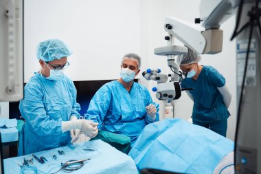 Yetenekli cerrah ve tıbbi ekibi yaşlı bir hastaya hassas bir göz ameliyatı yaparak en son tıbbi teknoloji ve ileri teknoloji ile görme yetisini geri kazandılar. Modern göz ameliyatı konsepti.