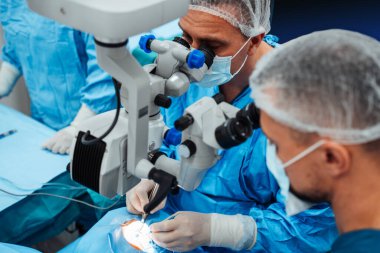 Yetenekli cerrah ve tıbbi ekibi yaşlı bir hastaya hassas bir göz ameliyatı yaparak en son tıbbi teknoloji ve ileri teknoloji ile görme yetisini geri kazandılar. Modern göz ameliyatı konsepti.