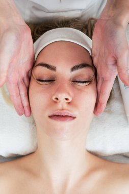 Güzeller güzeli genç bir kadın güzellik salonunda masaj yaptırıyor. Yüz masajı. Modern ve popüler kaplıca cilt ve vücut bakımı.