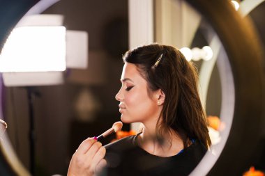 Profesyonel güzellik uzmanı güzel genç bir kadının yüzüne makyaj yapıyor. Muhteşem bir kadın modelle profesyonel makyaj stüdyosu çalışması..