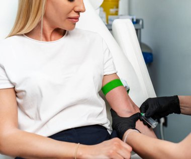 Tanımlanamayan siyah tıbbi eldivenli kadın laboratuvar asistanı modern kozmetik uygulaması için hastanın kolundan venöz kan alıyor. Modern güzellik ve kozmetik tedavileri. Yakın çekim..