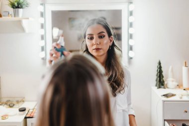 Makyaj süreci. Makyaj için makyaj yapan profesyonel bir sanatçı. Güzellik salonundaki güzel sarışın kadının portresi. Önde gelen güzel yüzük ışığına bak.