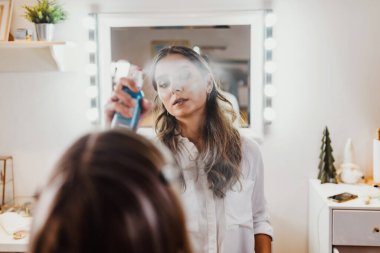 Makyaj süreci. Makyaj için makyaj yapan profesyonel bir sanatçı. Güzellik salonundaki güzel sarışın kadının portresi. Önde gelen güzel yüzük ışığına bak.