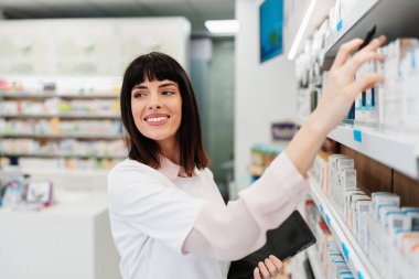 Güzel bir eczacı bir eczanede çalışıyor ve stok alımı yapıyor. Pozitif sağlık çalışanı portresi ya da iş yerinde çalışan bir kimyager..