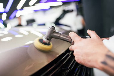 Modern bir araba atölyesinde profesyonel araç cilalama ve detay verme servisi. Parlak ışıklandırılmış çalışma alanı, büyük ışıklı. Yüksek kaliteli araba valelik kavramı.