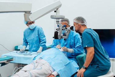 Yetenekli cerrah ve tıbbi ekibi yaşlı bir hastaya hassas bir göz ameliyatı yaparak en son tıbbi teknoloji ve ileri teknoloji ile görme yetisini geri kazandırıyor. Modern göz ameliyatı konsepti.