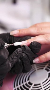 Profesyonel manikürcü ya da kuaför müşteri tırnağına oje sürerken tırnak törpüsü kullanıyor. Yakın çekim. Yüzeyin derinliği. Modern güzellik SPA ve kozmetik konsepti.