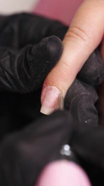 Profesyonel manikürcü ya da kuaför müşteri tırnağına oje sürerken tırnak törpüsü kullanıyor. Yakın çekim. Yüzeyin derinliği. Modern güzellik SPA ve kozmetik konsepti.