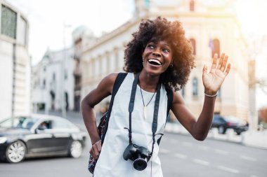 Genç siyah bayan turist güzel bir Avrupa şehrinin sokaklarında yürümekten zevk alıyor. O mutlu ve fotoğraf makinesini fantastik mimari fotoğraflar çekmek için kullanıyor. Parlak güneşli bir gün.