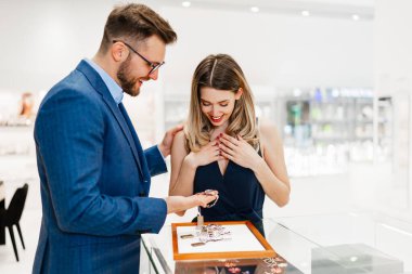 Modern kuyumcuda tatil alışverişinde eğlenen güzel bir çift. Erkekler moda ve tüketim kavramı.