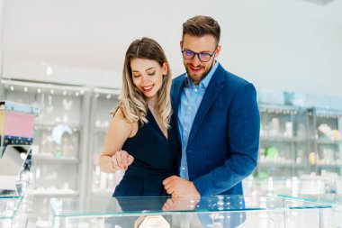 Modern kuyumcuda alışveriş yapan güzel bir çift. Genç bir kadın denesin. Muhteşem, pahalı kolye ve küpeler. Moda tarzı ve tüketim konsepti.