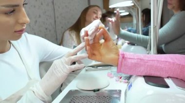 Modern bir güzellik salonunda çalışan profesyonel manikürcüler. Tatmin olmuş kadın müşteriler kaplıca merkezinde manikür tedavisi görüyor..