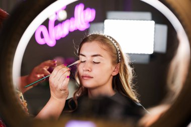 Profesyonel güzellik uzmanı güzel genç bir kadının yüzüne makyaj yapıyor. Muhteşem bir kadın modelle profesyonel makyaj stüdyosu çalışması..