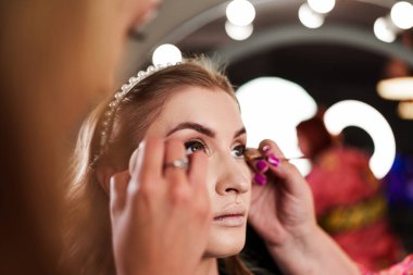Profesyonel güzellik uzmanı güzel genç bir kadının yüzüne makyaj yapıyor. Muhteşem bir kadın modelle profesyonel makyaj stüdyosu çalışması..