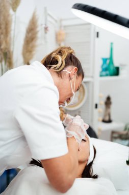 Güzel, genç bir kadın profesyonel makyaj tedavisi görüyor. Modern yüz ve kaş dövmesi çizimi. Güzellik ve kozmetik sektörü. 