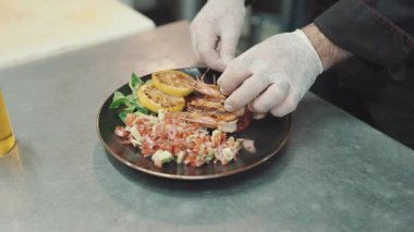 Yakışıklı sakallı profesyonel şef restoran mutfağında çalışıyor. O, balık ve deniz ürünleriyle sağlıklı lezzetli yemekler hazırlar..