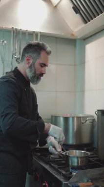 Yakışıklı sakallı profesyonel şef restoran mutfağında çalışıyor. O, balık ve deniz ürünleriyle sağlıklı lezzetli yemekler hazırlar..