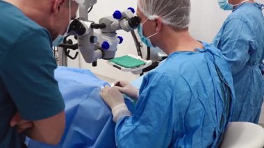 Yetenekli cerrah ve tıbbi ekibi yaşlı bir hastaya hassas bir göz ameliyatı yaparak en son tıbbi teknoloji ve ileri teknoloji ile görme yetisini geri kazandırıyor. Modern göz ameliyatı konsepti.