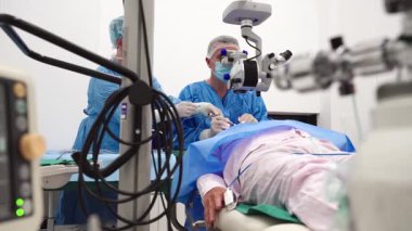 Yetenekli cerrah ve tıbbi ekibi yaşlı bir hastaya hassas bir göz ameliyatı yaparak en son tıbbi teknoloji ve ileri teknoloji ile görme yetisini geri kazandırıyor. Modern göz ameliyatı konsepti.