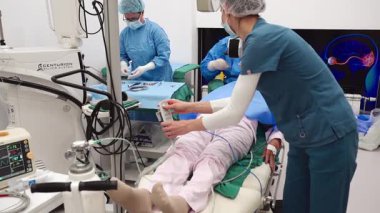 Yetenekli cerrah ve tıbbi ekibi yaşlı bir hastaya hassas bir göz ameliyatı yaparak en son tıbbi teknoloji ve ileri teknoloji ile görme yetisini geri kazandırıyor. Modern göz ameliyatı konsepti.