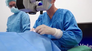 Yetenekli cerrah ve tıbbi ekibi yaşlı bir hastaya hassas bir göz ameliyatı yaparak en son tıbbi teknoloji ve ileri teknoloji ile görme yetisini geri kazandırıyor. Modern göz ameliyatı konsepti.