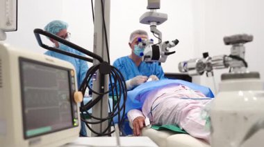 Yetenekli cerrah ve tıbbi ekibi yaşlı bir hastaya hassas bir göz ameliyatı yaparak en son tıbbi teknoloji ve ileri teknoloji ile görme yetisini geri kazandırıyor. Modern göz ameliyatı konsepti.