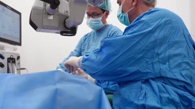 Yetenekli cerrah ve tıbbi ekibi yaşlı bir hastaya hassas bir göz ameliyatı yaparak en son tıbbi teknoloji ve ileri teknoloji ile görme yetisini geri kazandırıyor. Modern göz ameliyatı konsepti.