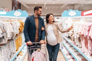 Çekici, orta yaşlı bir çift yeni bebekleri için elbise ve eşyalar almaktan zevk alıyor. Bebek dükkanında ya da dükkanda güzel bir çift. Bebek konsepti bekleniyor..