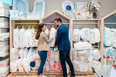 Çekici, orta yaşlı bir çift yeni bebekleri için elbise ve eşyalar almaktan zevk alıyor. Bebek dükkanında ya da dükkanda güzel bir çift. Bebek konsepti bekleniyor..