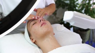 Güzel, rahat, genç bir kadın gözleri kapalı uzanmış güzellik merkezinde ya da kuaförde yüz masajı yapıyor. Bayan müşteri cilt bakımı tedavisinden zevk alıyor. Sağlık ve güzellik kavramı.