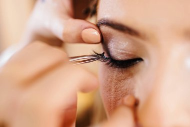 Profesyonel güzellik uzmanı güzel genç bir kadının yüzüne makyaj yapıyor. Muhteşem bir kadın modelle profesyonel makyaj stüdyosu çalışması..