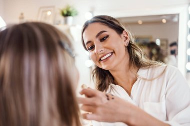 Profesyonel güzellik uzmanı güzel genç bir kadının yüzüne makyaj yapıyor. Muhteşem bir kadın modelle profesyonel makyaj stüdyosu çalışması..