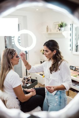 Profesyonel güzellik uzmanı güzel genç bir kadının yüzüne makyaj yapıyor. Muhteşem bir kadın modelle profesyonel makyaj stüdyosu çalışması..