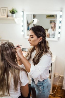 Profesyonel güzellik uzmanı güzel genç bir kadının yüzüne makyaj yapıyor. Muhteşem bir kadın modelle profesyonel makyaj stüdyosu çalışması..