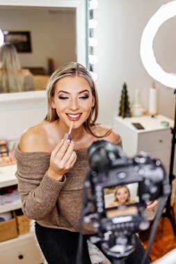 Güzel bayan çevrimiçi içerik kozmetikçisi makyaj yapıyor ve izleyicilere bazı iş araçlarını açıklıyor. Günlük kaydı ve çevrimiçi kanal çalışması. 