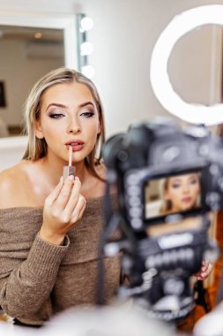 Güzel bayan çevrimiçi içerik kozmetikçisi makyaj yapıyor ve izleyicilere bazı iş araçlarını açıklıyor. Günlük kaydı ve çevrimiçi kanal çalışması. 