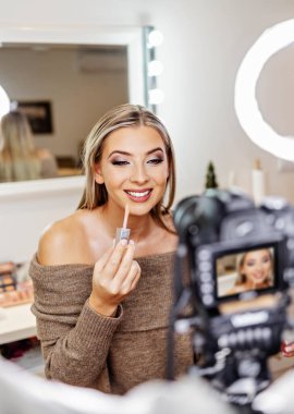 Güzel bayan çevrimiçi içerik kozmetikçisi makyaj yapıyor ve izleyicilere bazı iş araçlarını açıklıyor. Günlük kaydı ve çevrimiçi kanal çalışması. 