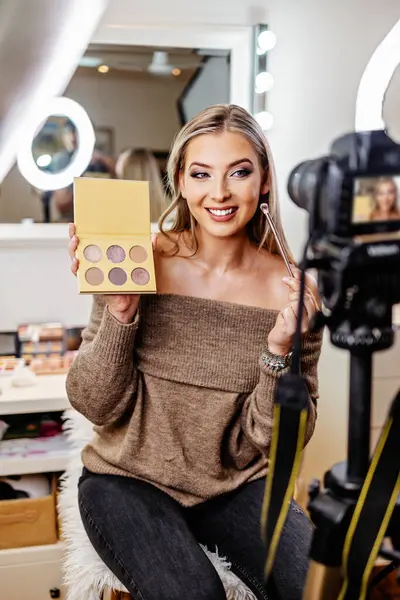 Güzel bayan çevrimiçi içerik kozmetikçisi makyaj yapıyor ve izleyicilere bazı iş araçlarını açıklıyor. Günlük kaydı ve çevrimiçi kanal çalışması. 