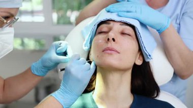 Güzel esmer kadın hasta botulinyum toksin iğneleri ya da hyaluronik asit doldurucu ile tıbbi ve güzellik tedavisine hazırlanıyor..