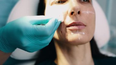 Çekici genç bir kadın güzellik kliniğinde gençleştirici yüz enjeksiyonu yaptırıyor. Güzellik uzmanı kadın kırışıklıklarını botulinyum toksin iğneleriyle ya da hyaluronik asit doldurucularıyla dolduruyor..