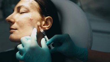 Çekici genç bir kadın güzellik kliniğinde gençleştirici yüz enjeksiyonu yaptırıyor. Güzellik uzmanı kadın kırışıklıklarını botulinyum toksin iğneleriyle ya da hyaluronik asit doldurucularıyla dolduruyor..