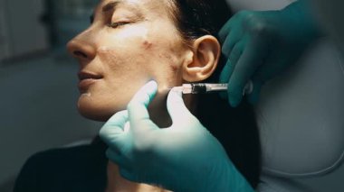 Çekici genç bir kadın güzellik kliniğinde gençleştirici yüz enjeksiyonu yaptırıyor. Güzellik uzmanı kadın kırışıklıklarını botulinyum toksin iğneleriyle ya da hyaluronik asit doldurucularıyla dolduruyor..
